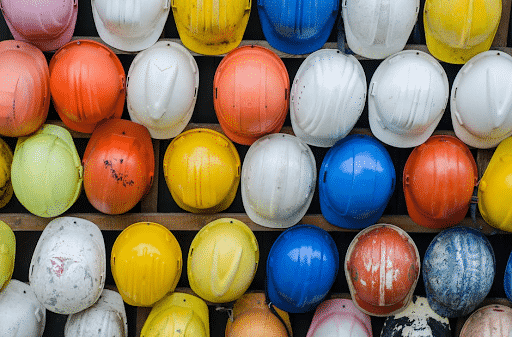A wall of several multicolored construction hardhats. 